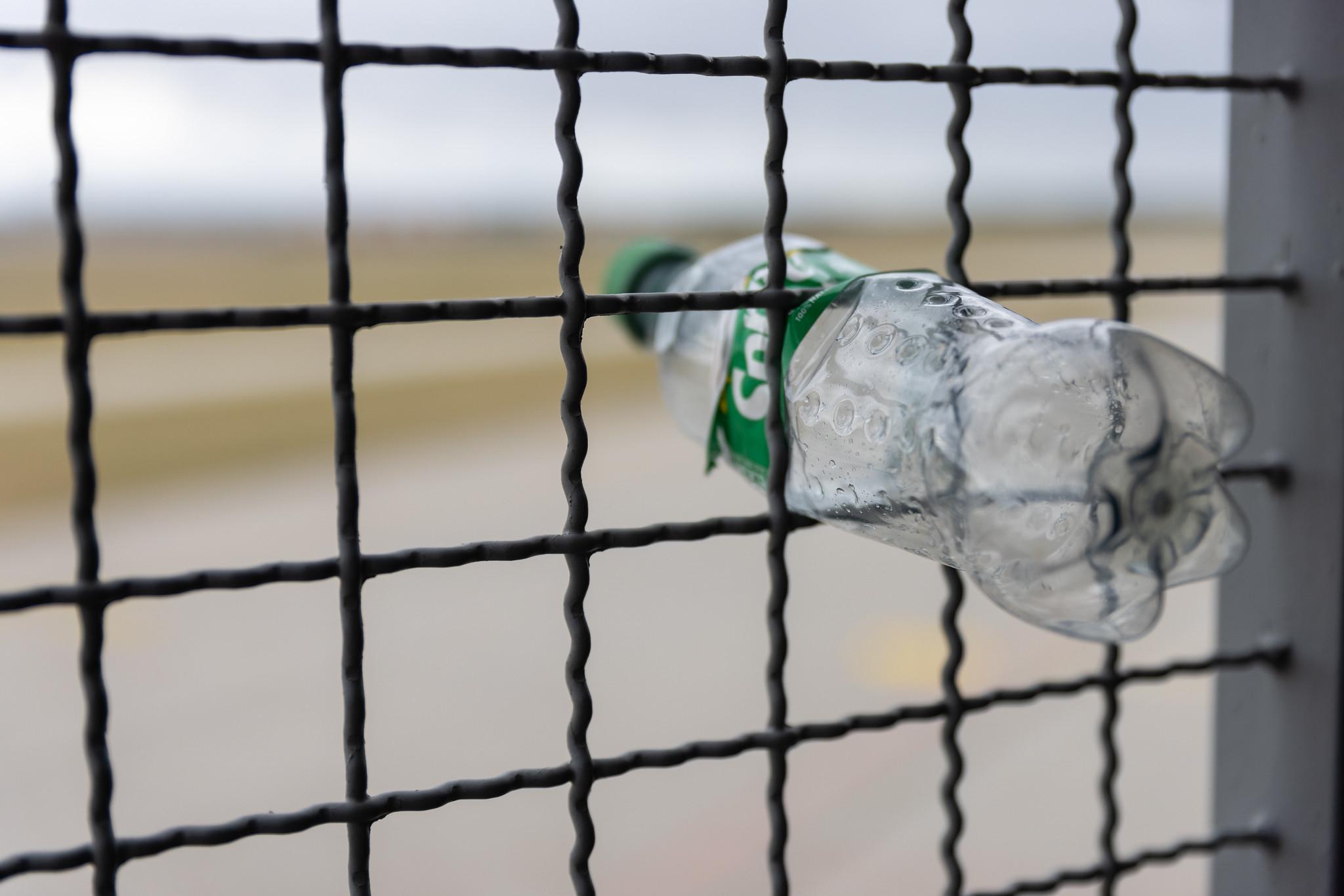 Hannover Airport: Zerdrückte Plastikflasche in Zaun